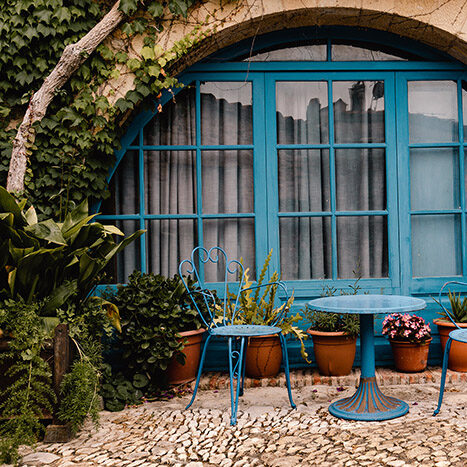 Terrasse de maison fleurie sol en pierres naturelle avec salon de jardin fer forgé